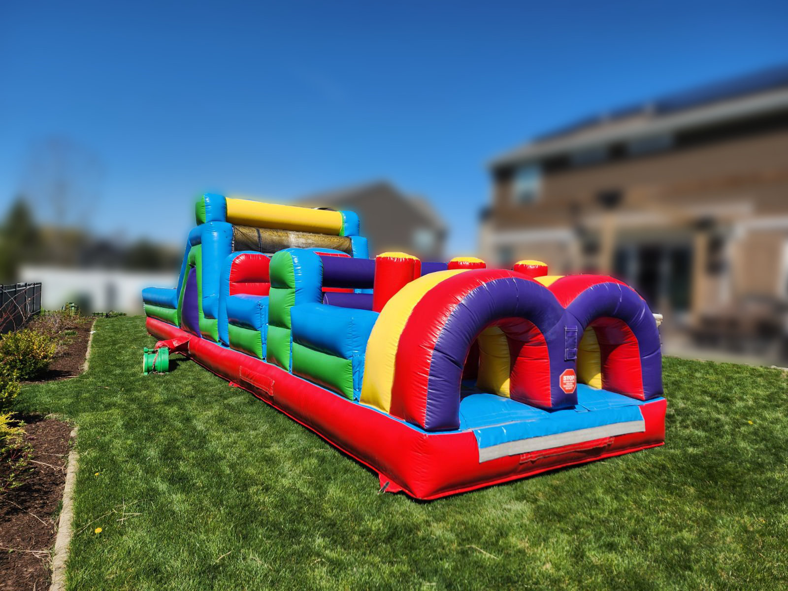 A colorful inflatable obstacle course is sitting on top of a lush green lawn.