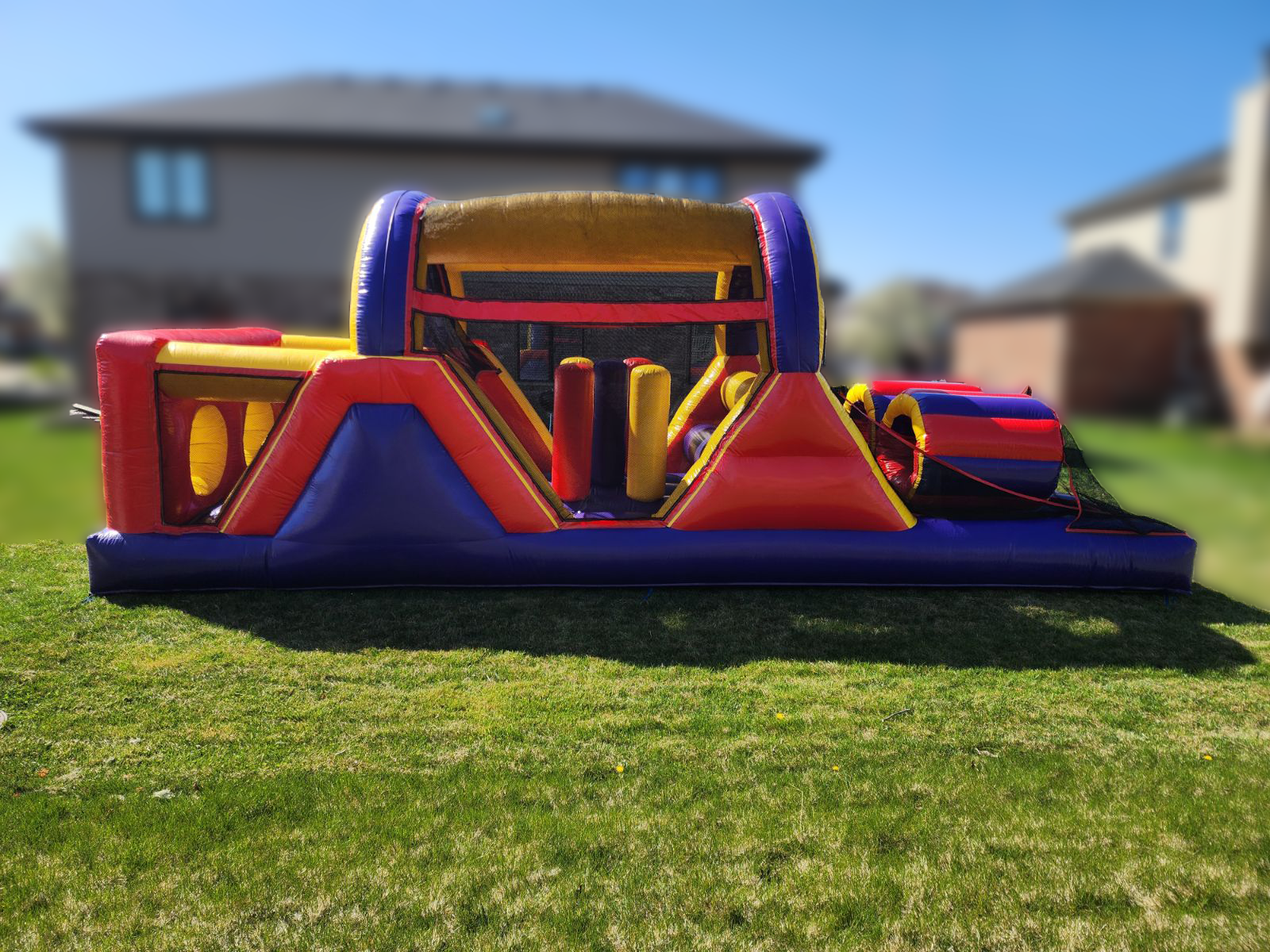 An inflatable obstacle course is sitting in the grass in front of a house.