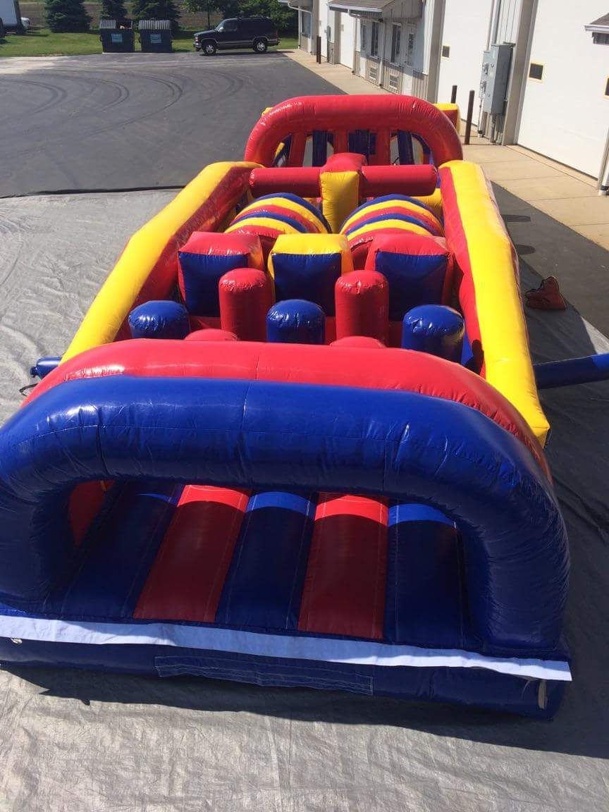 A red yellow and blue inflatable obstacle course is sitting on the ground