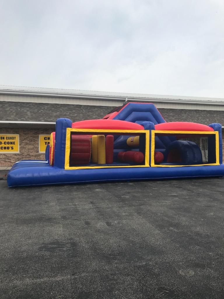 A large inflatable obstacle course is sitting in a parking lot in front of a building.
