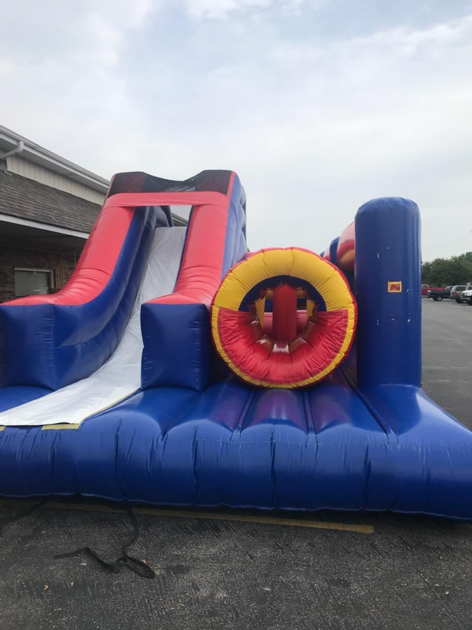 A blue and red bouncy house is sitting in a parking lot.