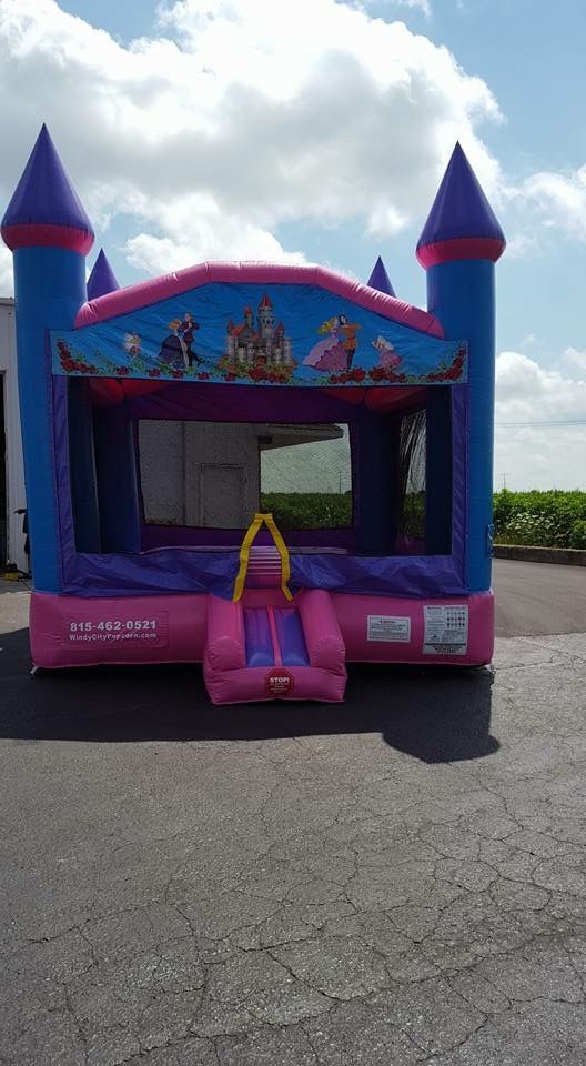 A pink and blue bouncy house in the shape of a castle.