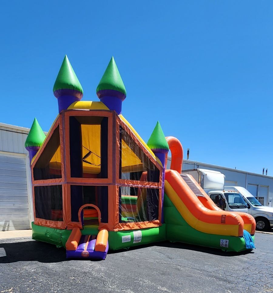 A colorful bouncy house with a slide is parked in a parking lot