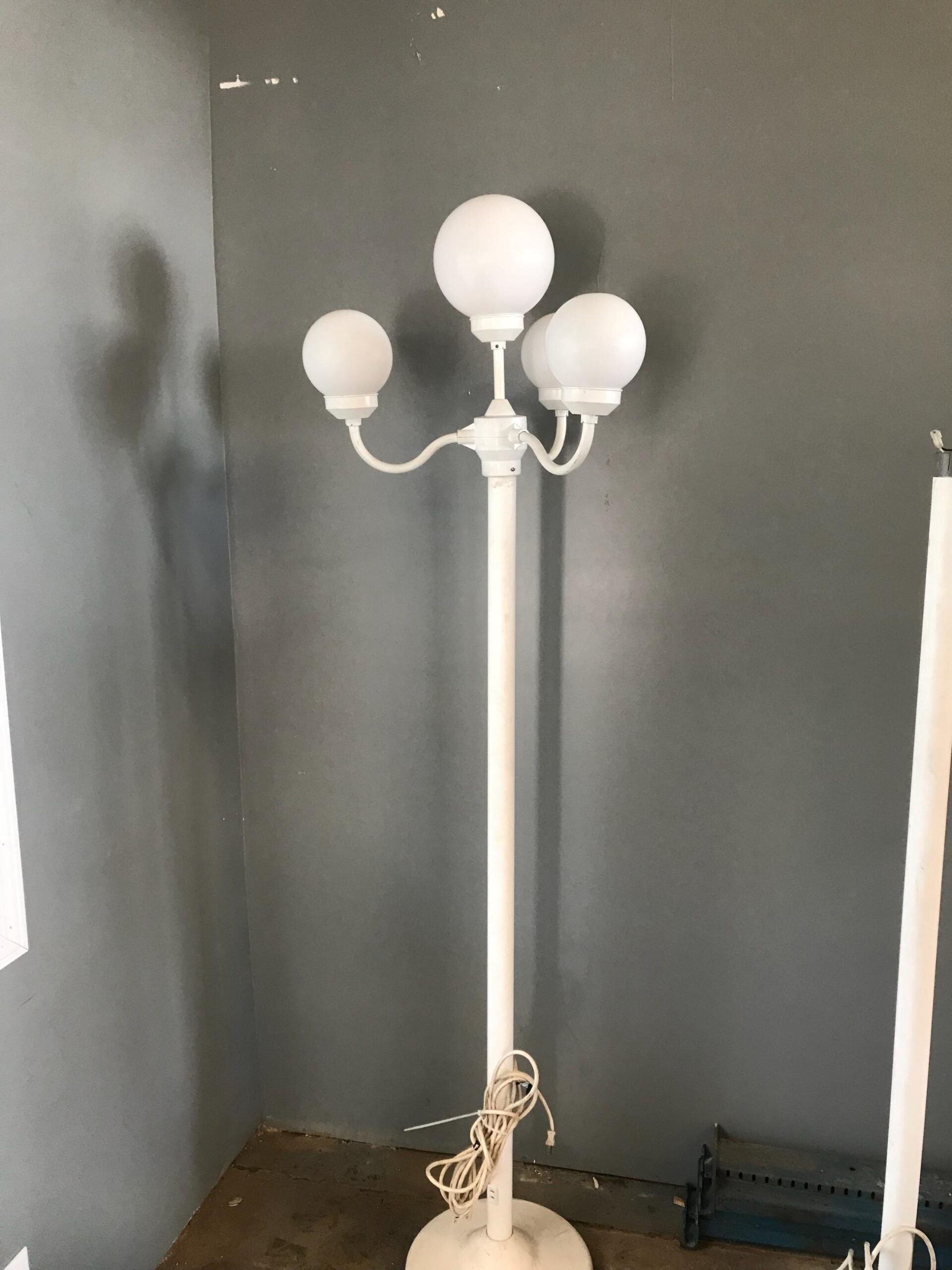 A white lamp is sitting in a corner of a room.