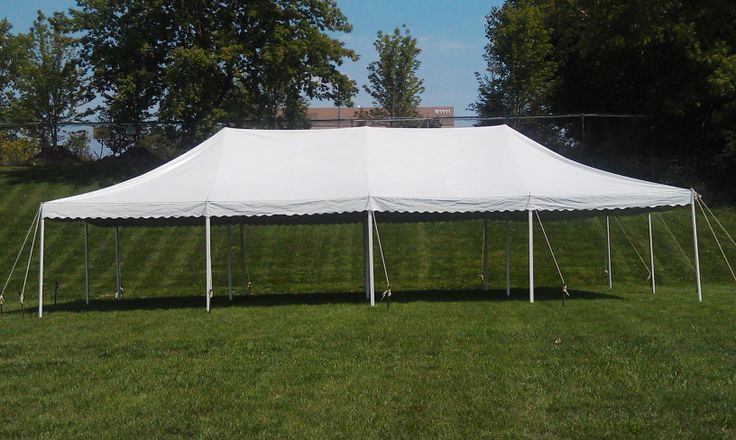 A large white tent is sitting in the middle of a lush green field.