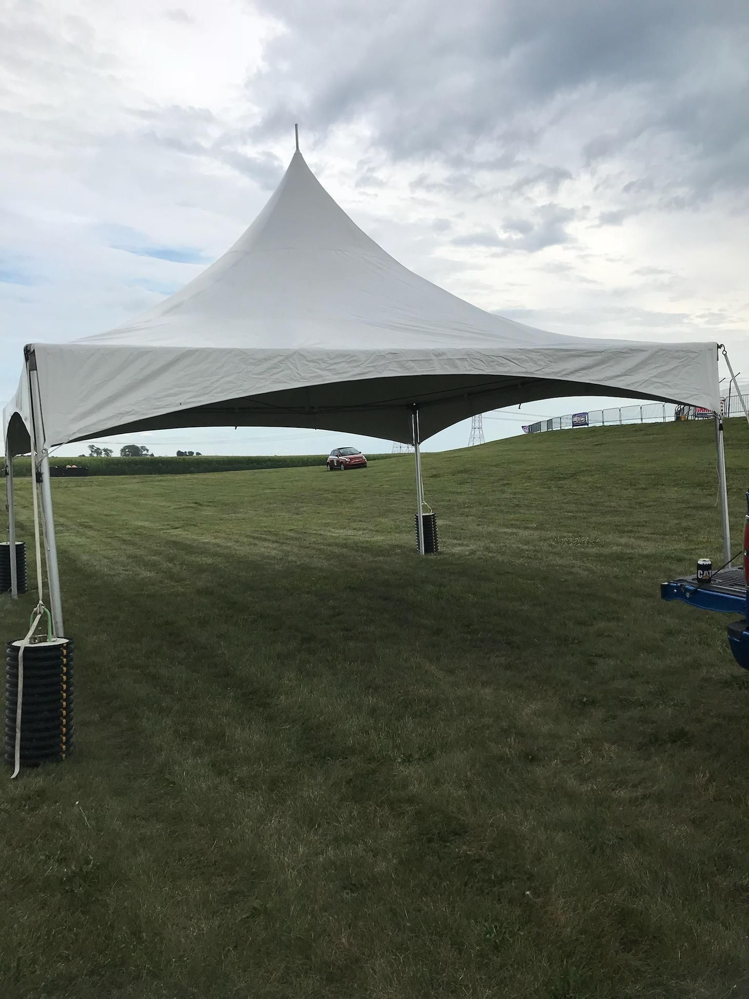 A white tent is sitting in the middle of a grassy field.