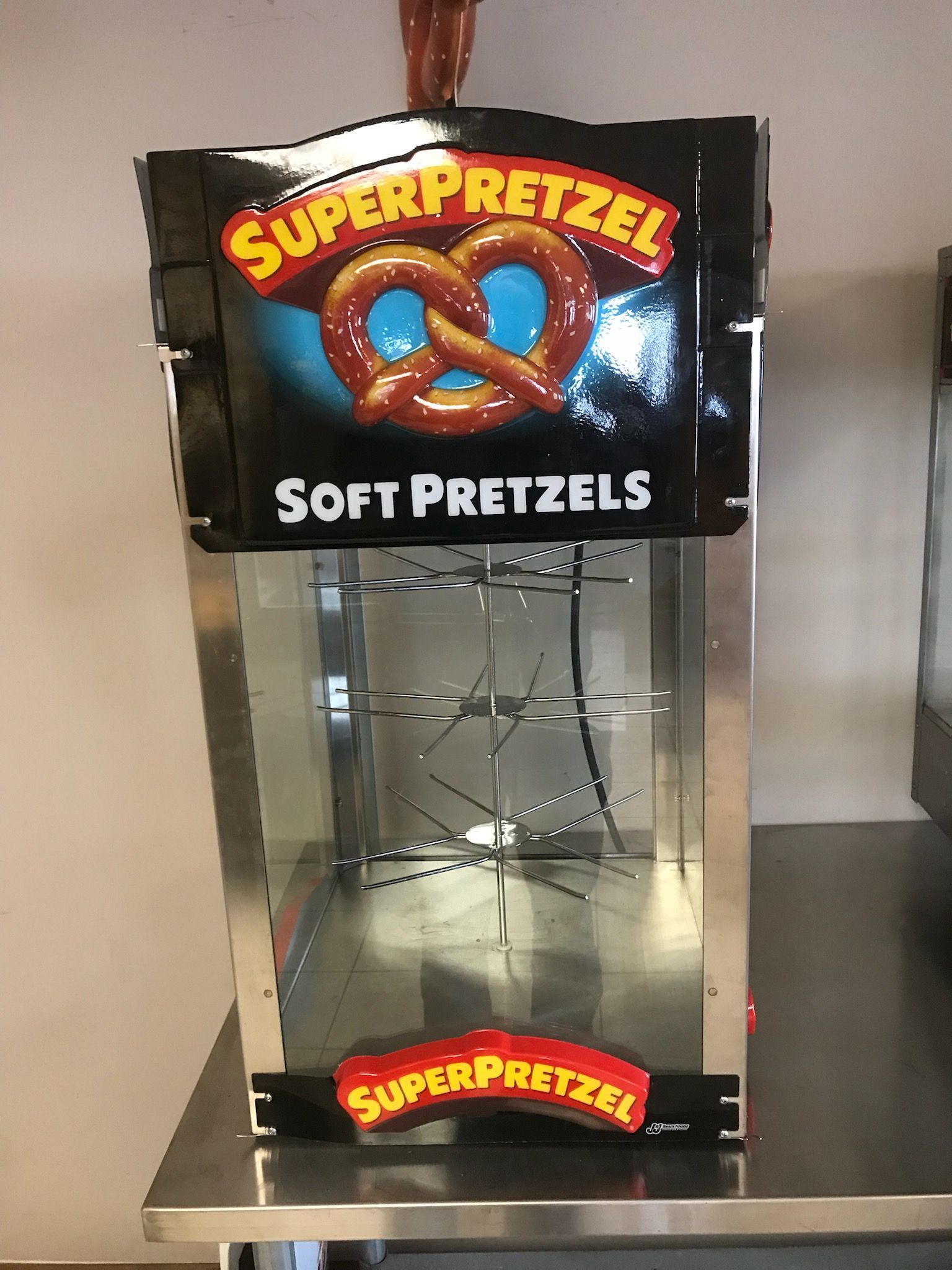 A super pretzel soft pretzel machine is sitting on a counter.