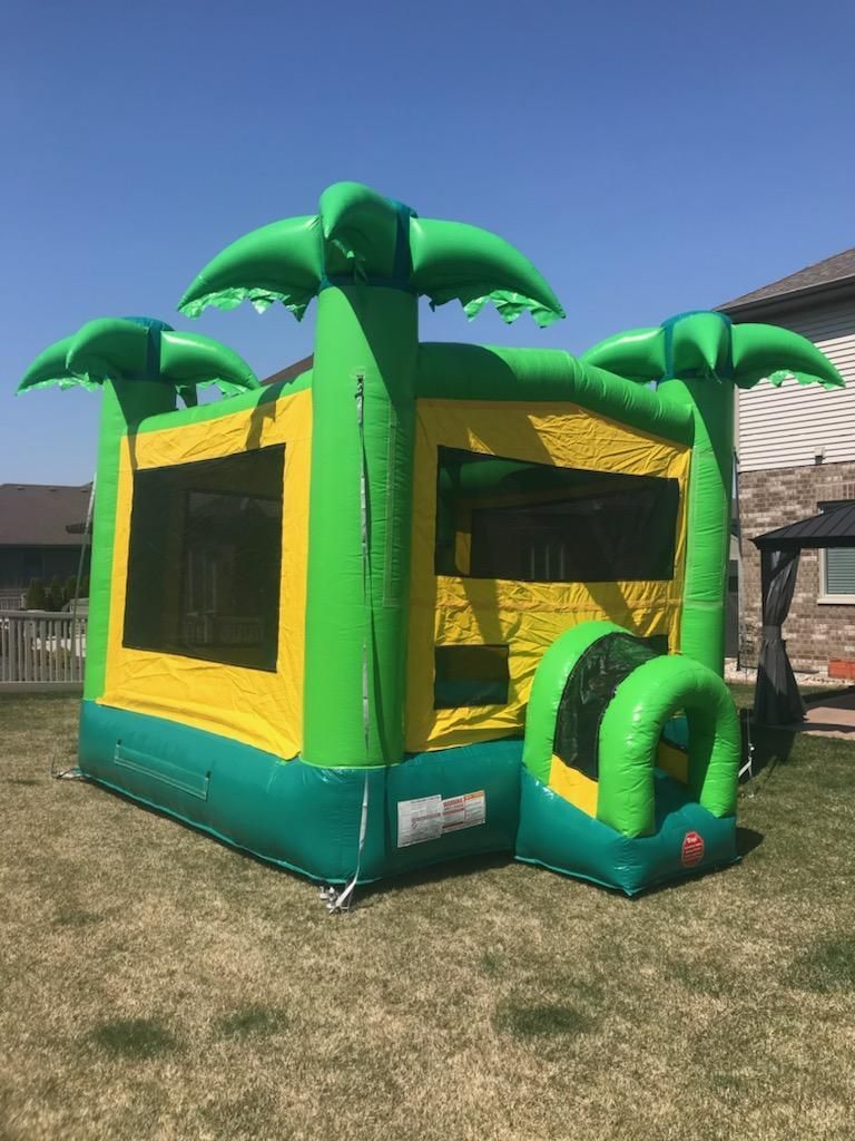 A green and yellow bouncy house with palm trees on top of it.