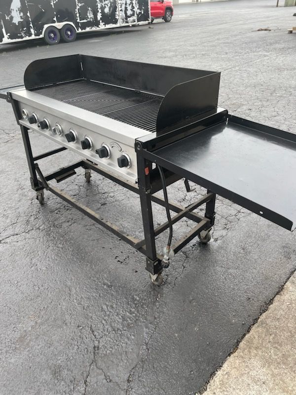 A grill is sitting on a cart on the side of the road.
