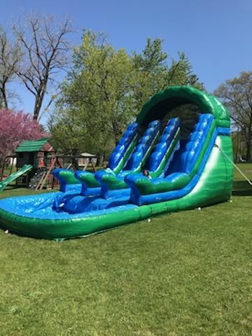 A large inflatable water slide is sitting on top of a lush green field.