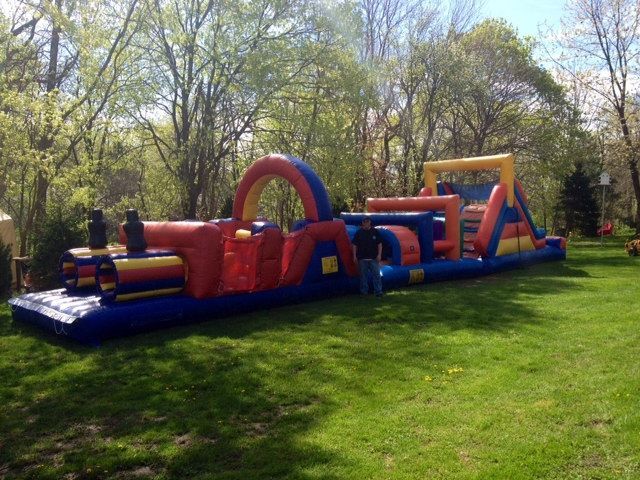 A man is standing in front of a large inflatable obstacle course.