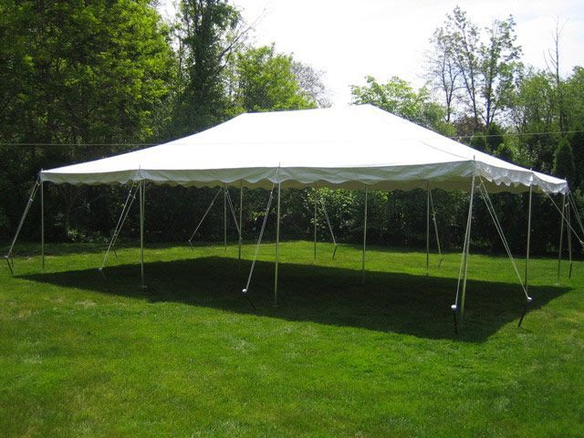 A large white tent is sitting in the middle of a lush green field.