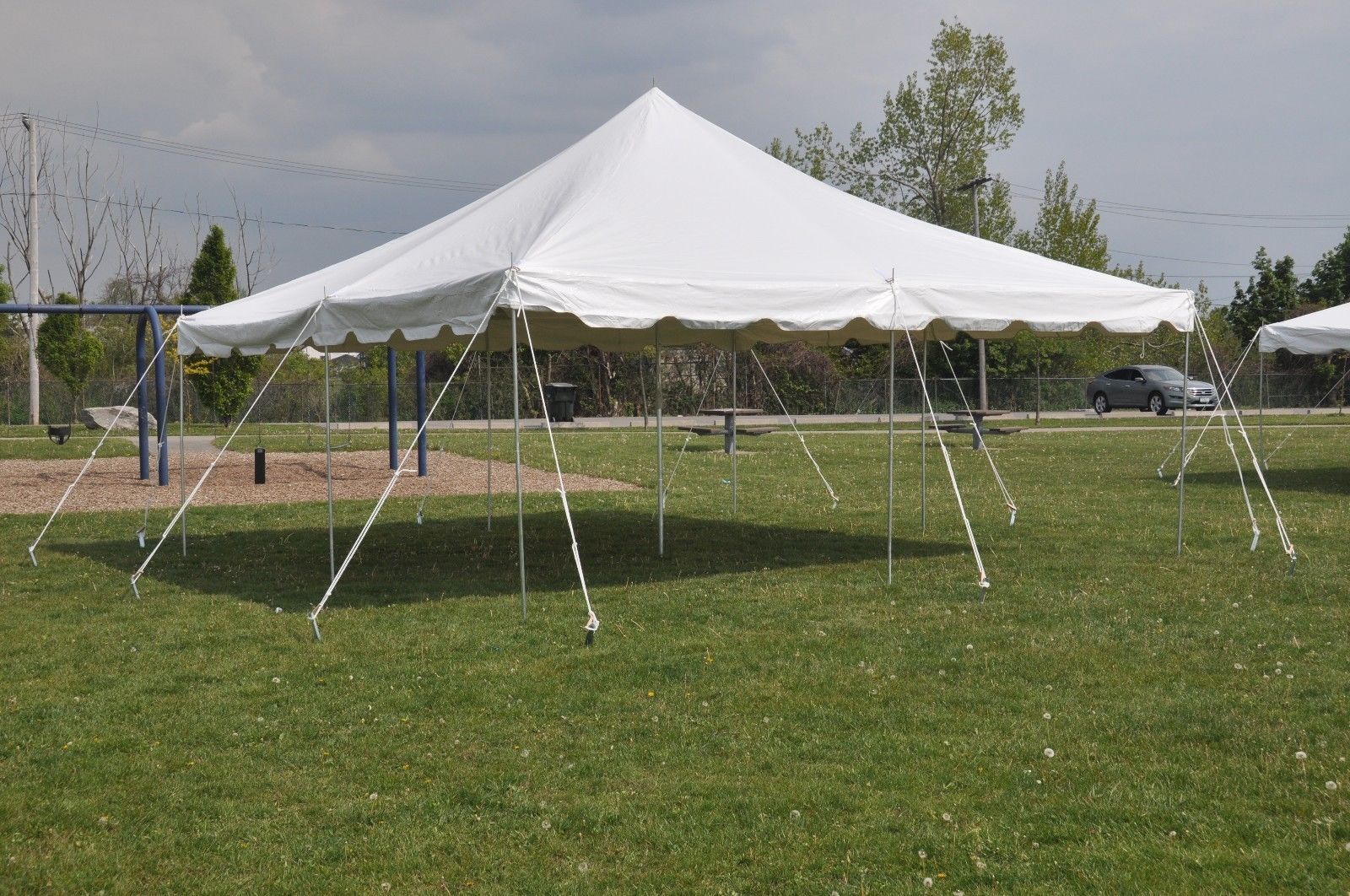 A white tent is sitting in the middle of a grassy field.