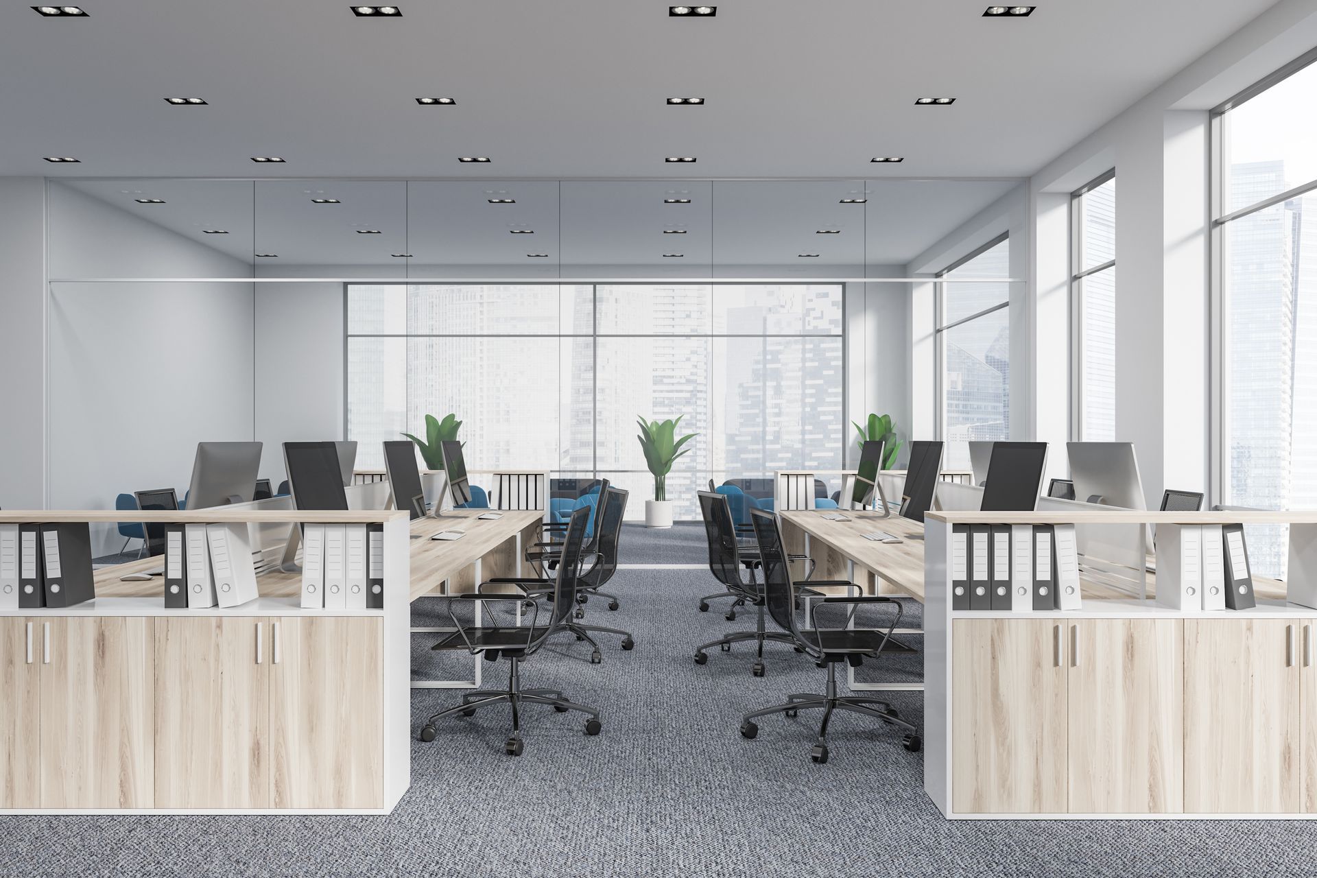 Modern open-plan office with desks, rolling chairs, glass partitions, and large windows