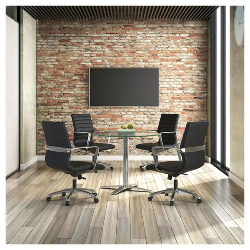 Modern meeting room with four black chairs, round table, brick wall, and wall-mounted screen