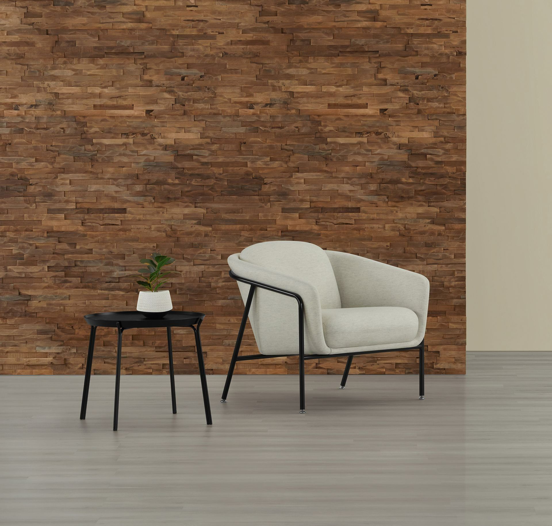 White armchair and black side table with plant against a brick wall in a minimalist room
