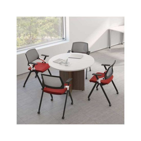 Round meeting table with four red office chairs in a bright corner room