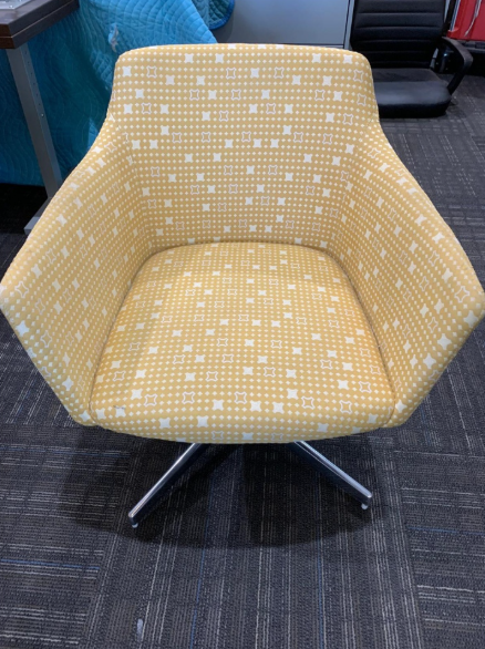Yellow patterned swivel lounge chair on a dark carpeted floor.