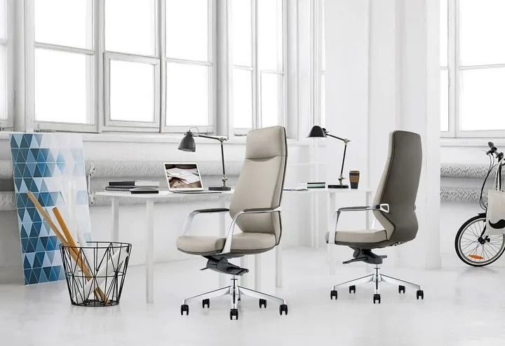 Modern white office with two beige swivel chairs, desks, lamps, and a bicycle by the window