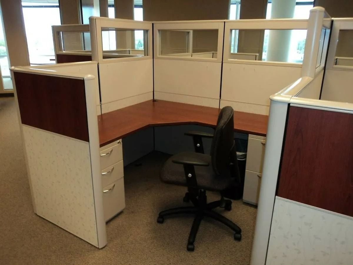 Empty beige office cubicle with wood accents and a black swivel chair