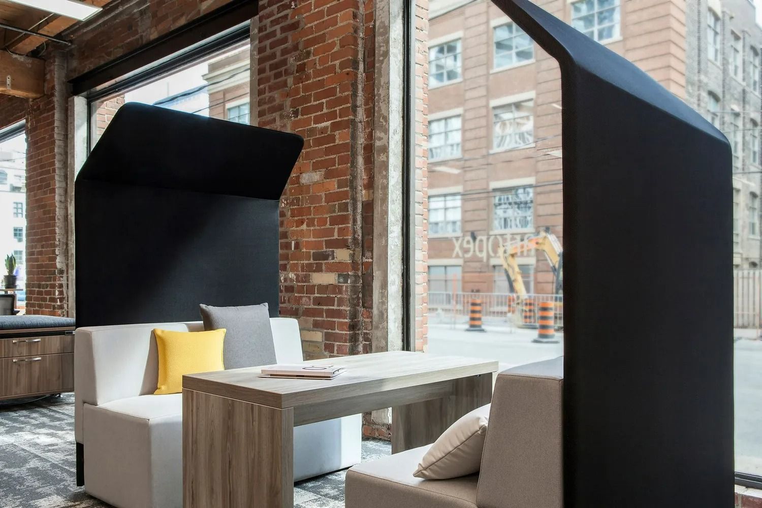 Modern lounge with black pod seats, white sofas, and a wooden table by large windows