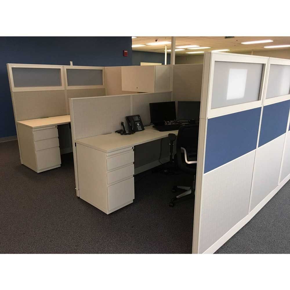 Empty office cubicles with beige desks and blue-and-white partition walls.