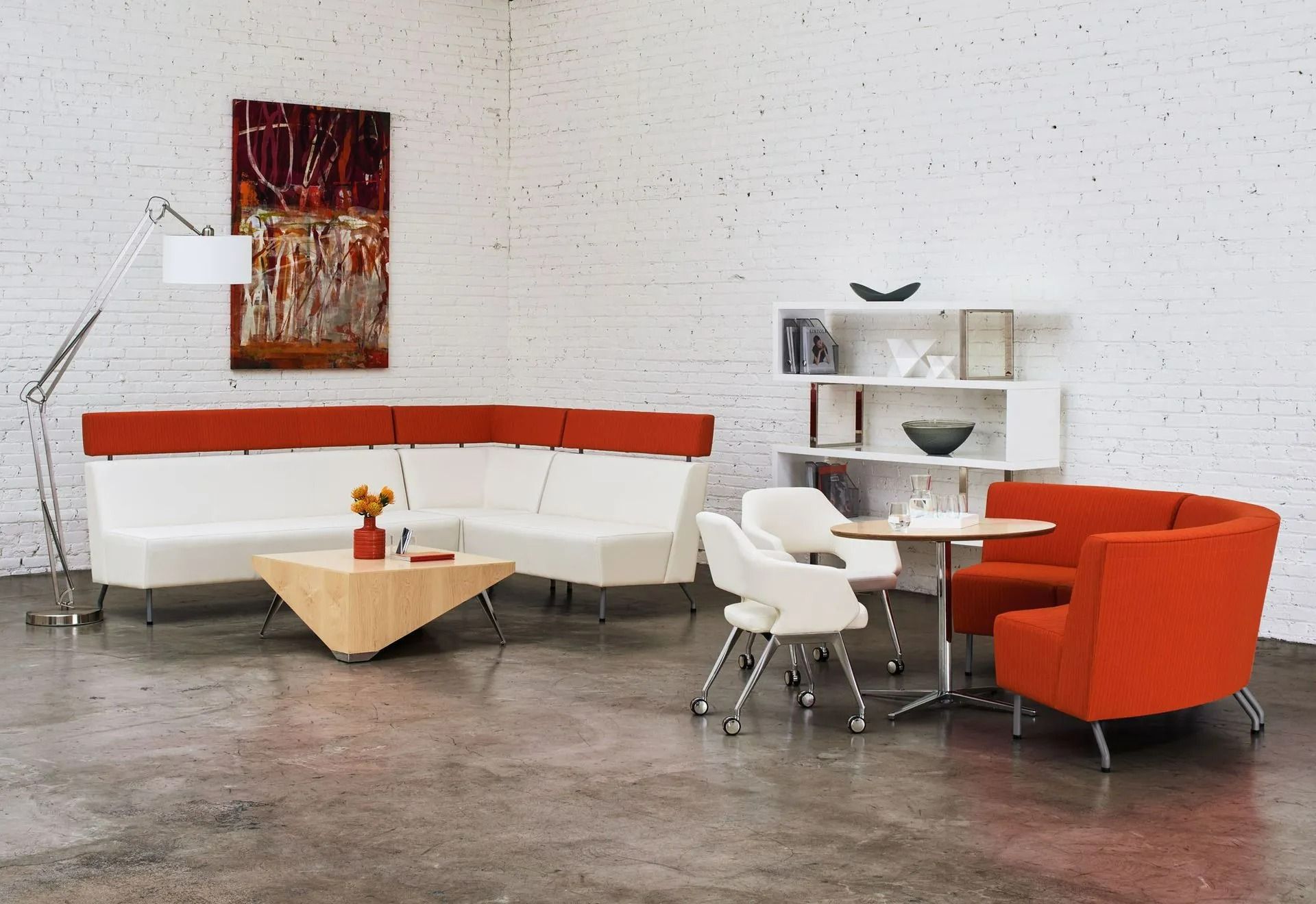 Modern lounge with orange and white seating, white tables, and wall art on a speckled wall.