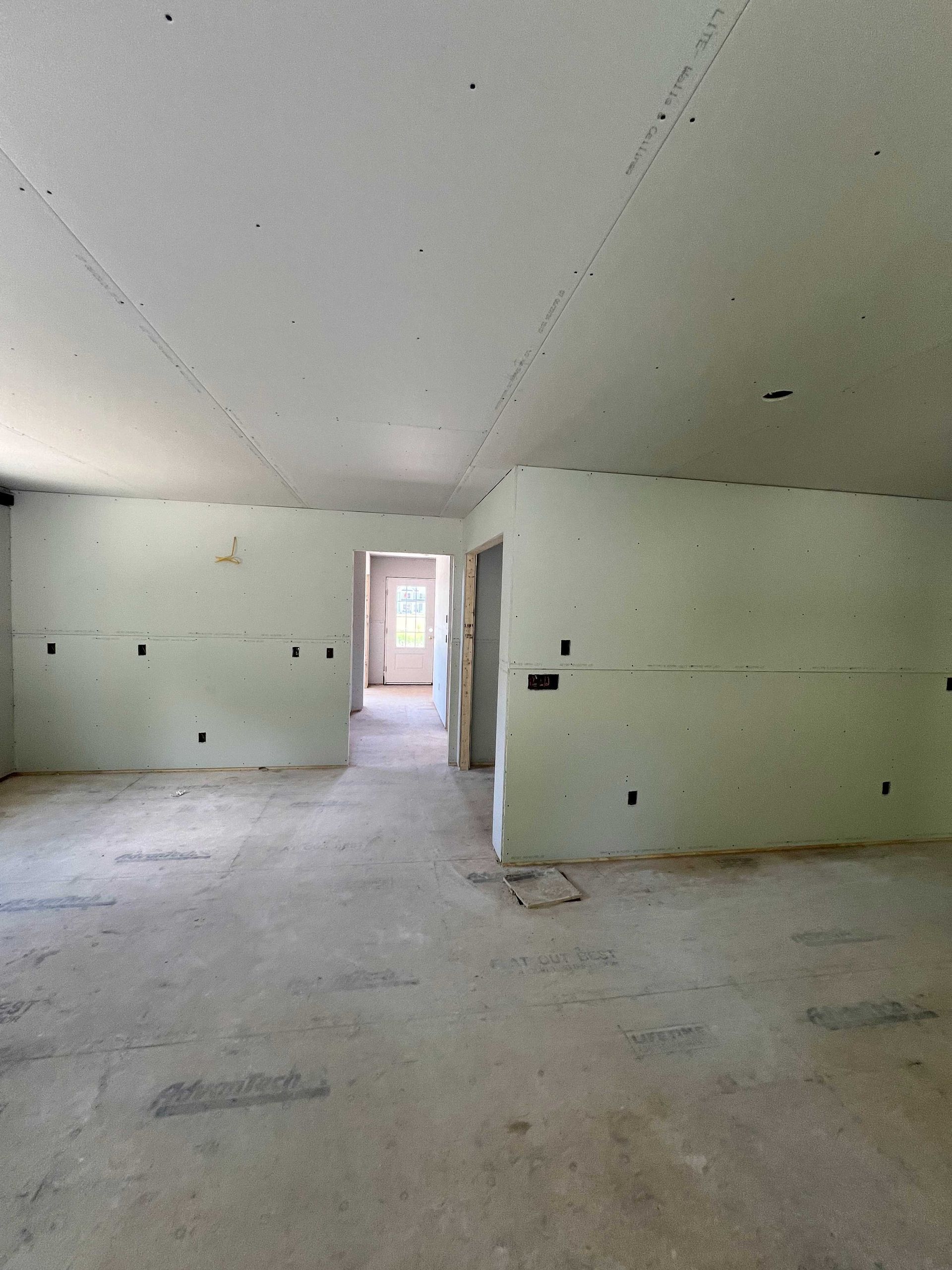 Interior of a room under construction, with exposed drywall walls and concrete floor.