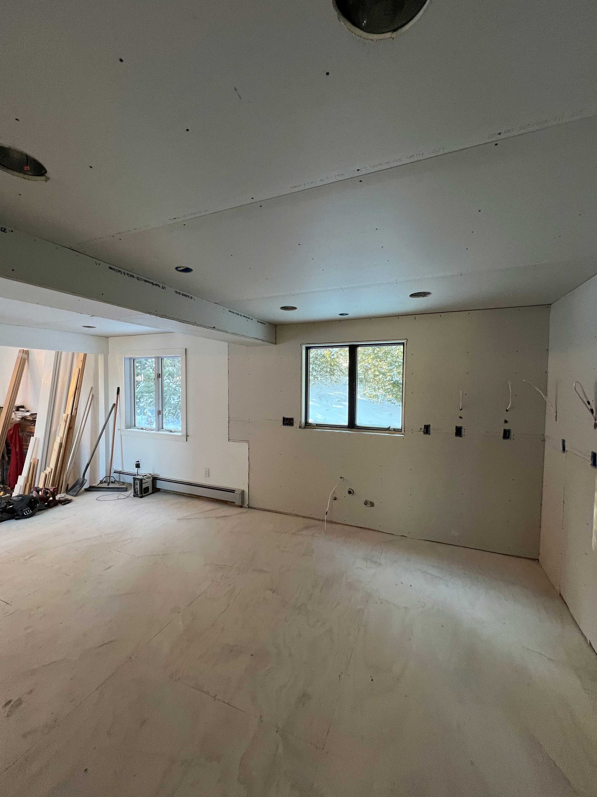 Empty room with drywall walls, windows, and exposed electrical boxes.