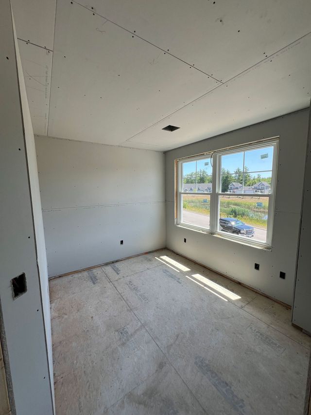 Unfinished room with drywall walls and window. Sunlight streams in. Electrical outlets visible.
