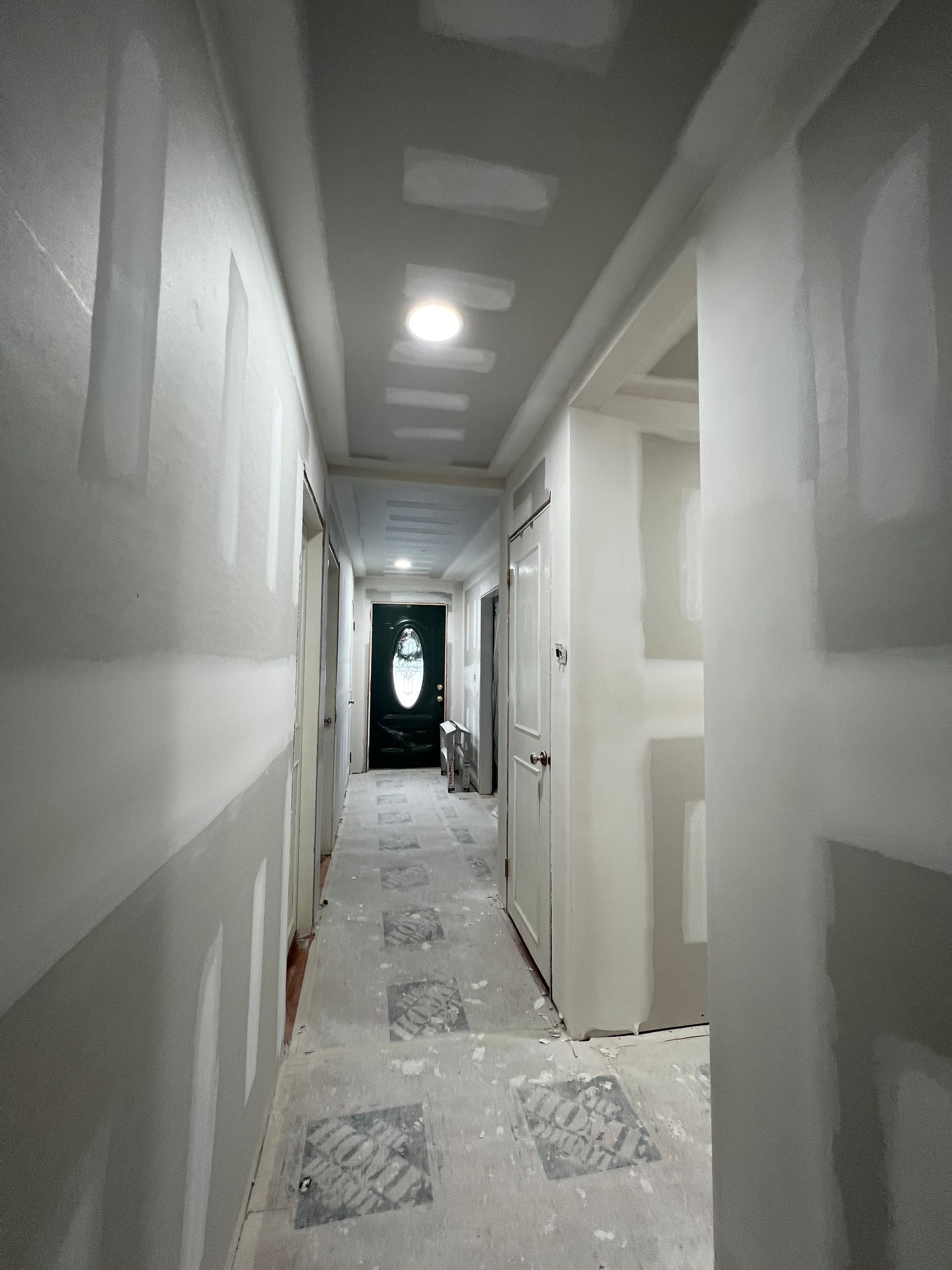 Narrow hallway under construction with drywall and unfinished surfaces.
