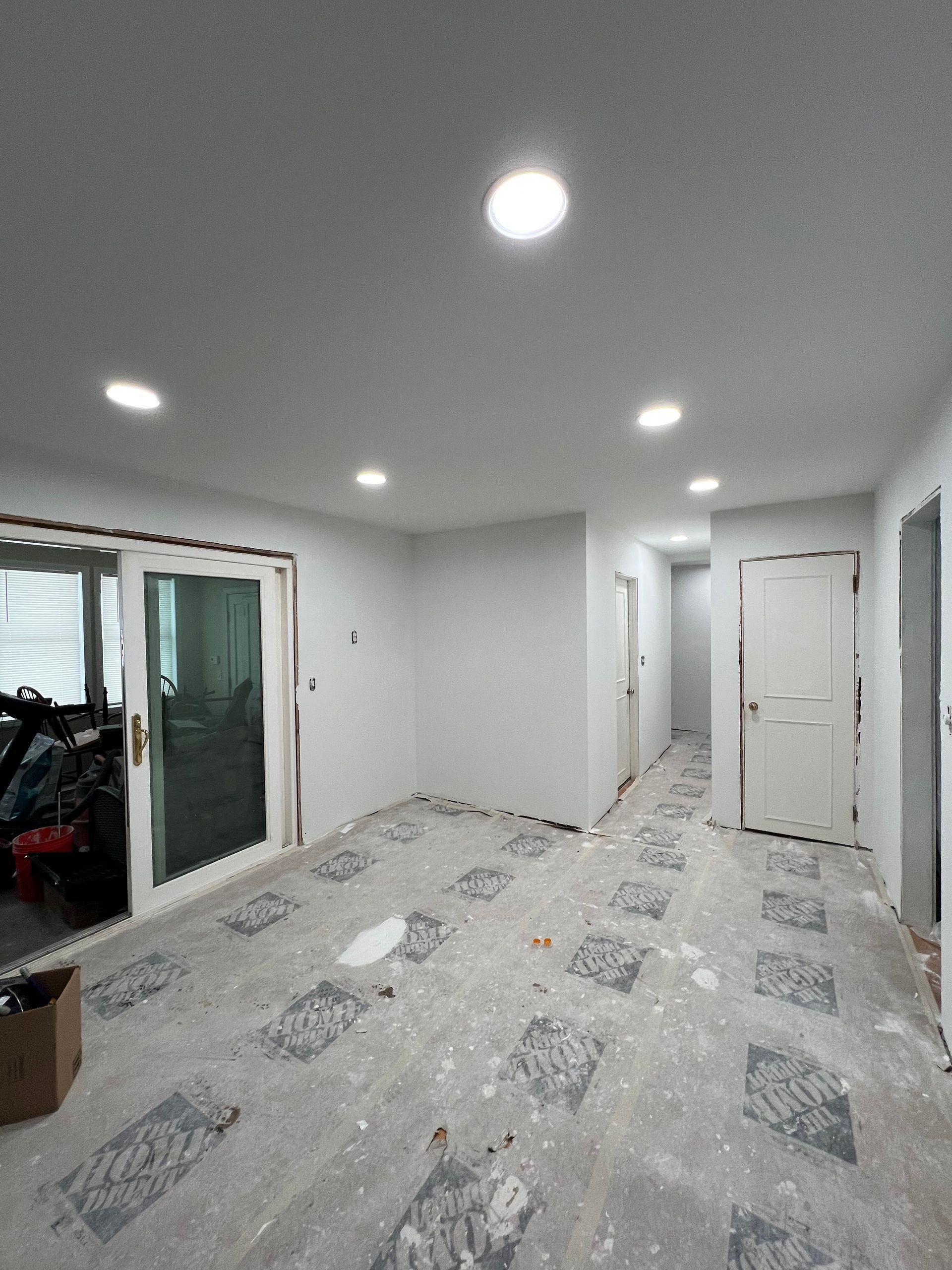 Room under renovation with recessed lighting, doors, and exposed flooring.