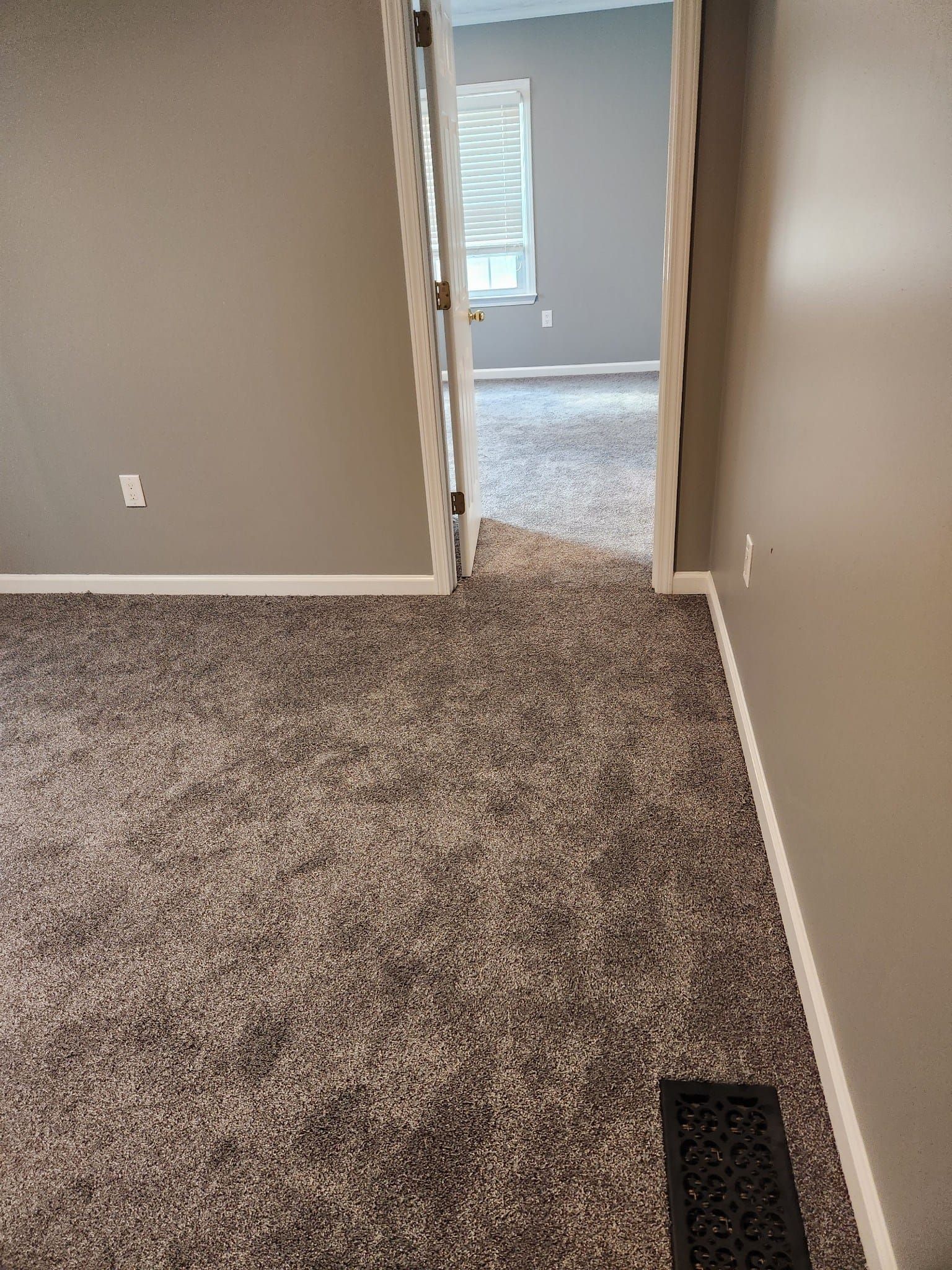 A doorway leads to another room, both with carpet. The walls are painted a neutral color.