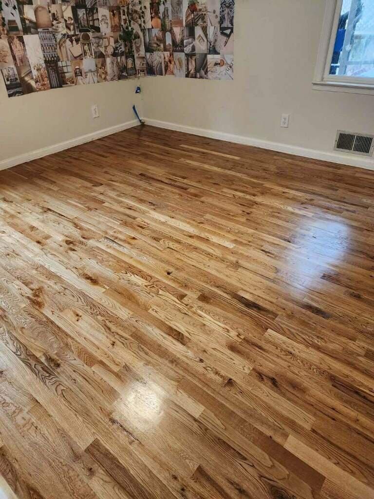 Wooden floor in a room, with a wall of photos and a window.