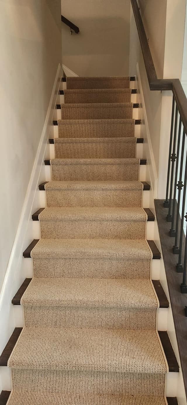 Staircase with woven tan carpet, white risers, and dark brown trim and handrail.