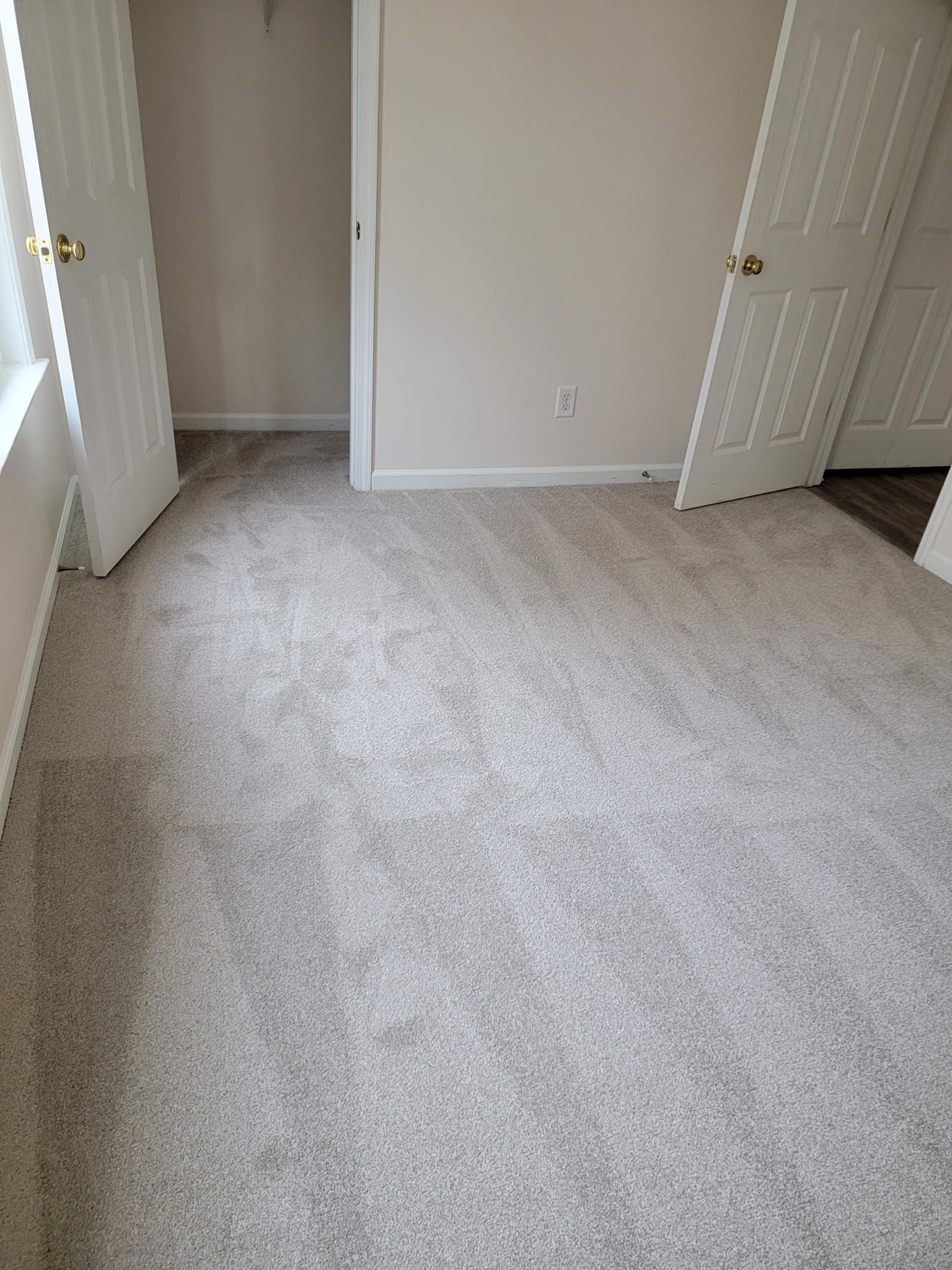 Empty bedroom with light gray carpet, off-white walls, and two white doors.