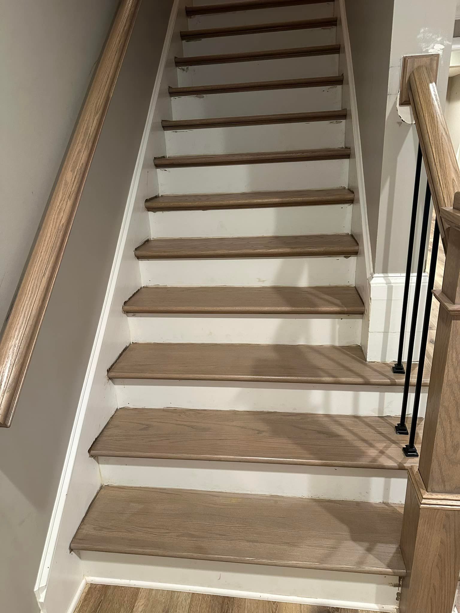 Wooden staircase with white risers, two handrails, going upward.
