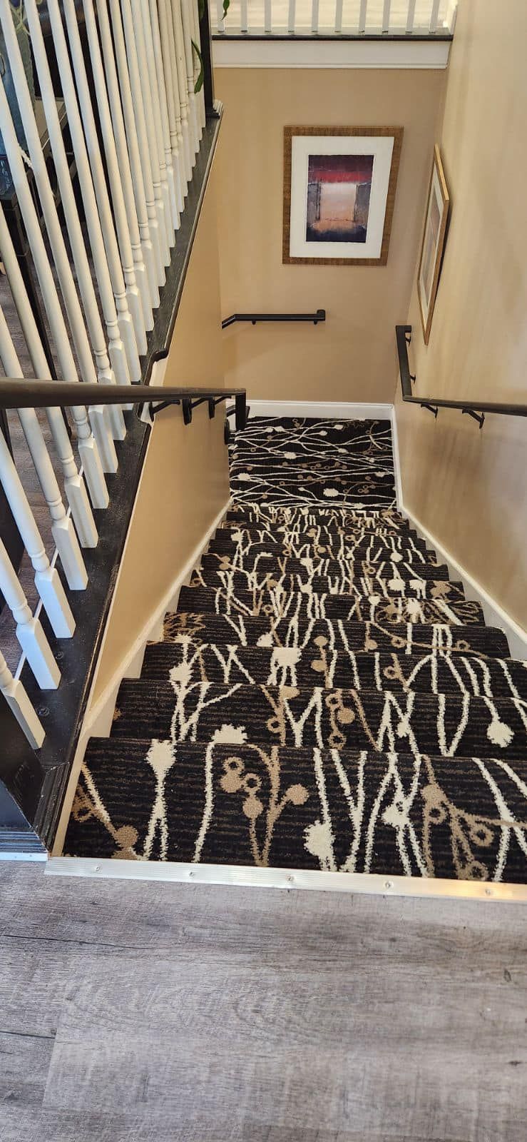 Staircase with patterned carpet and decorative wall art.