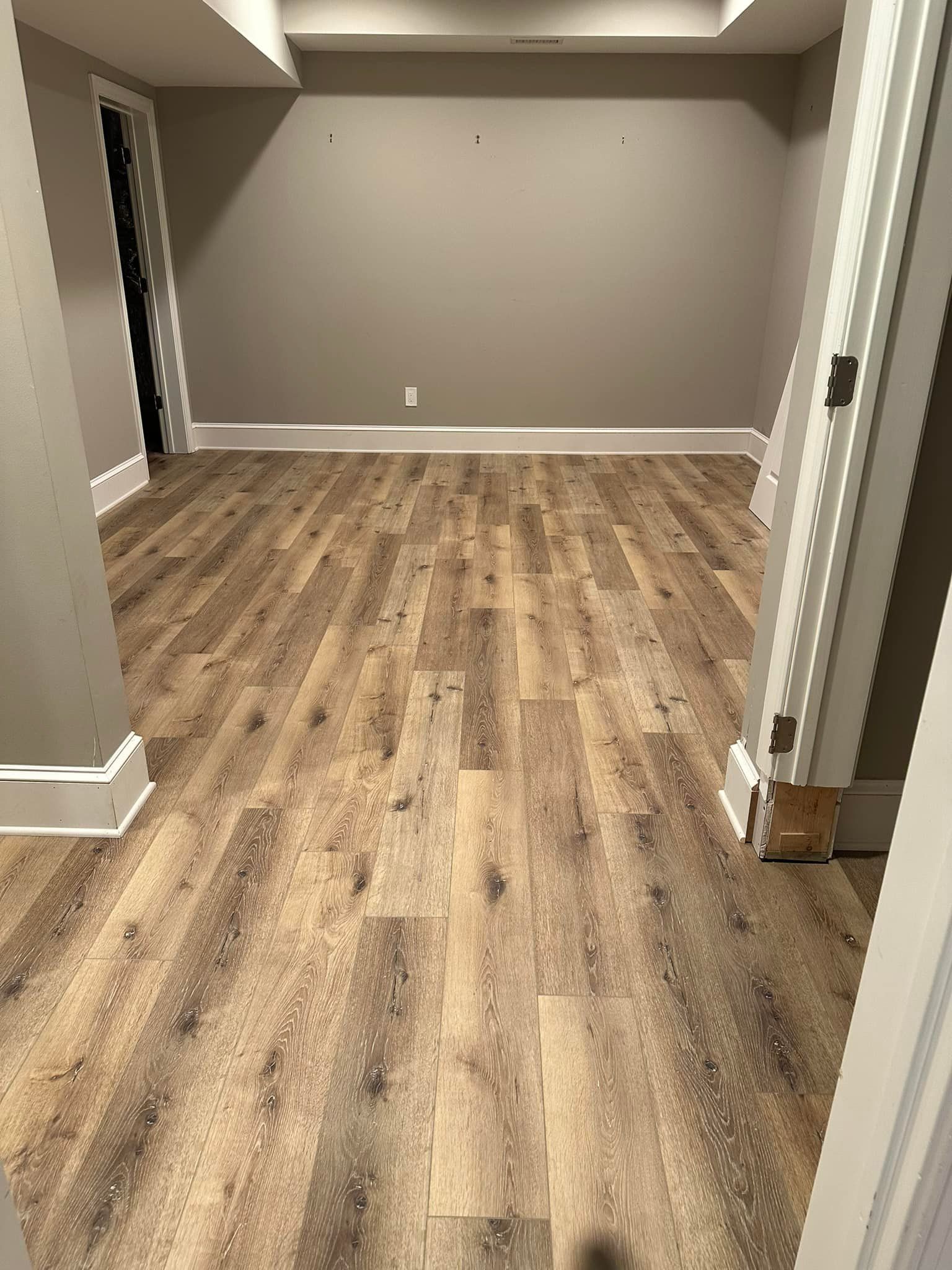Empty room with wood-look flooring, gray walls, and white trim.
