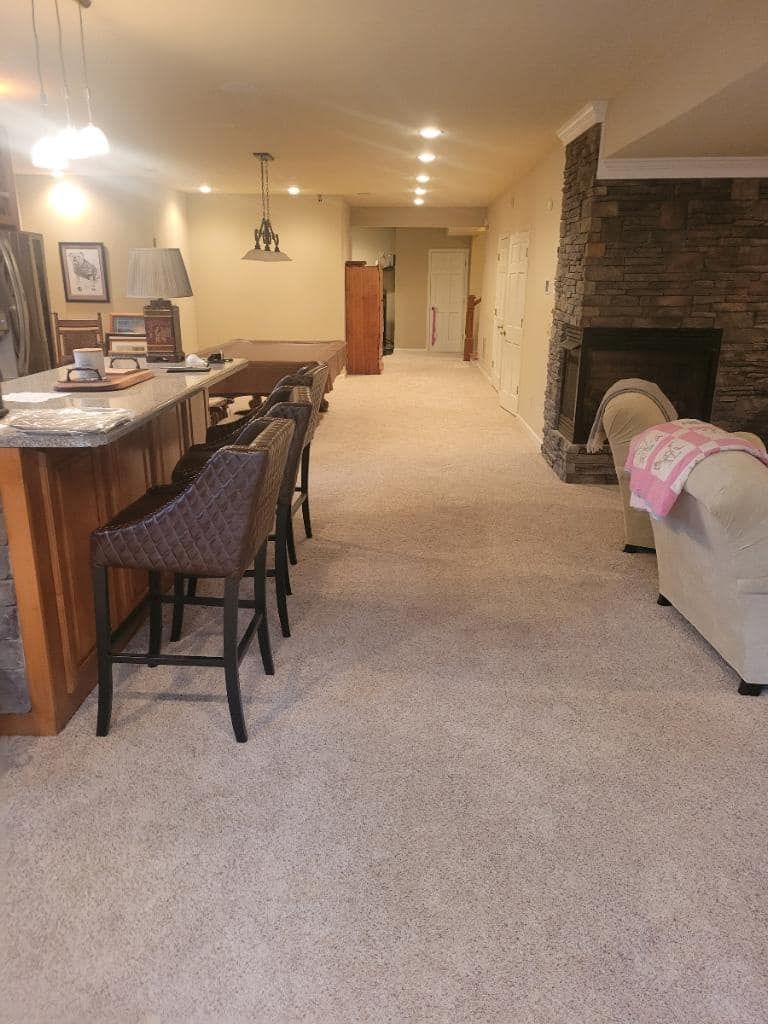 Bar area with stools, fireplace, and neutral carpeted floors.