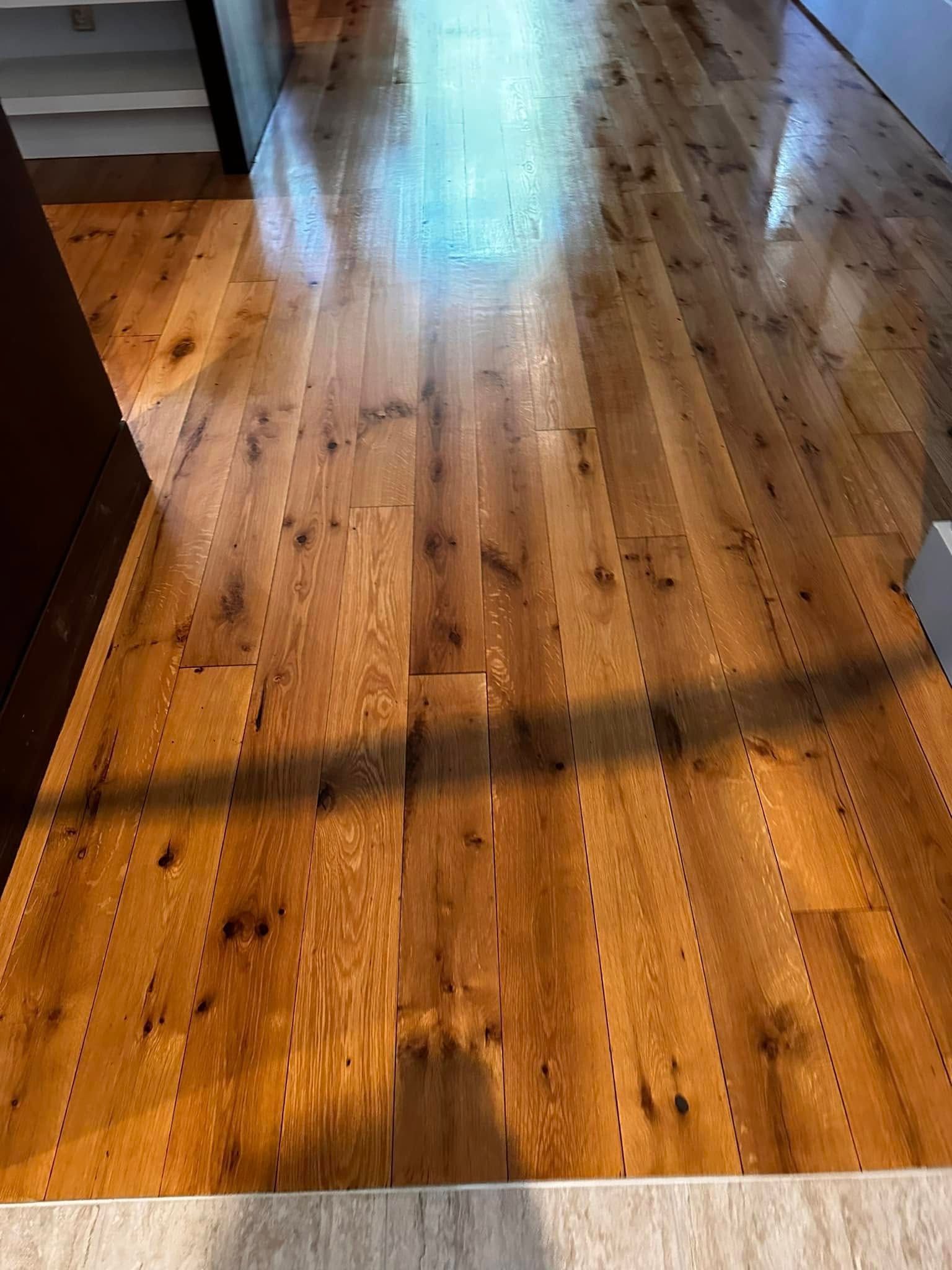 Hardwood floor with natural wood grain and knots, polished to a shine.
