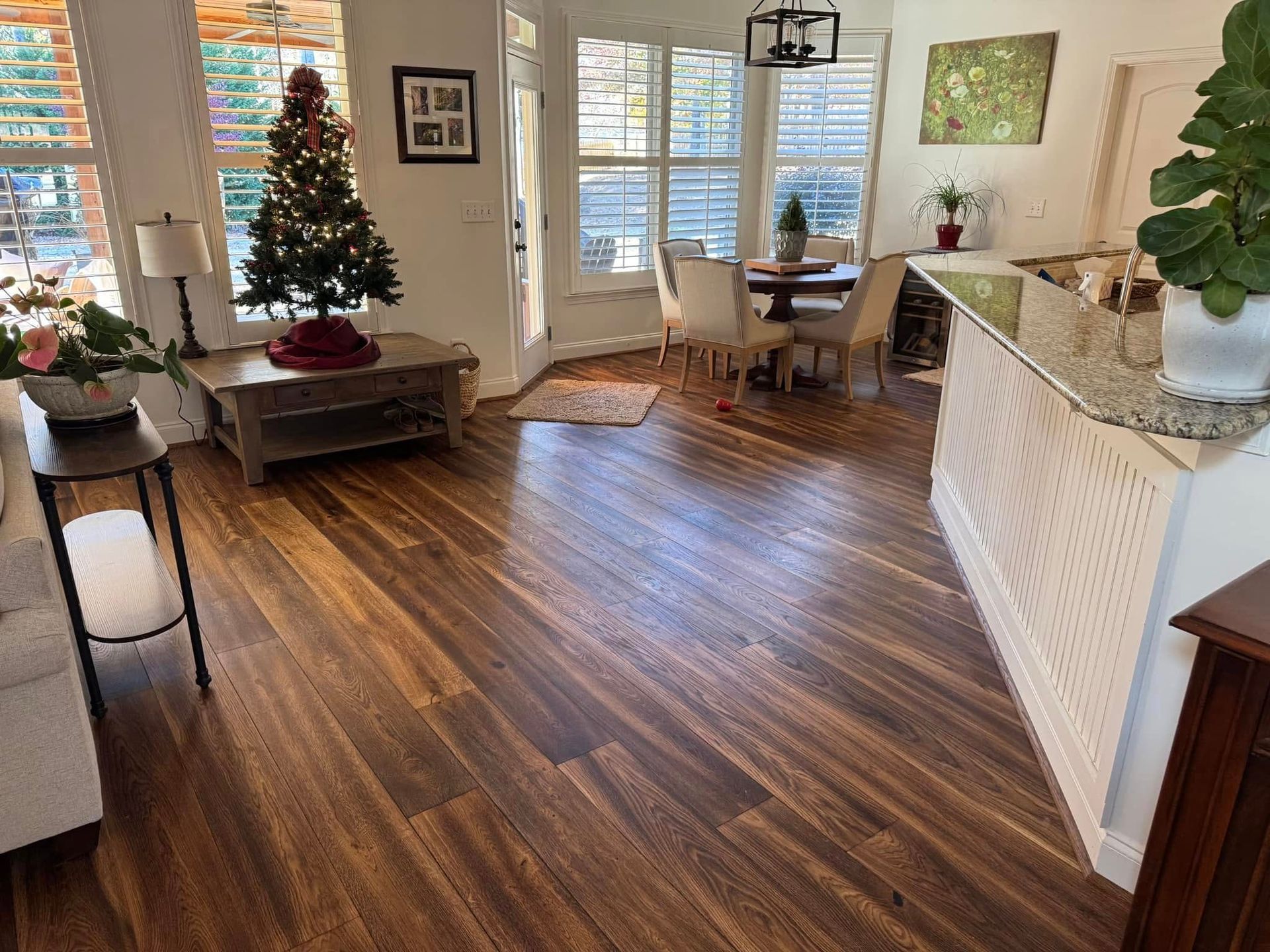 Living room with wood flooring, Christmas tree, dining area, and counter.