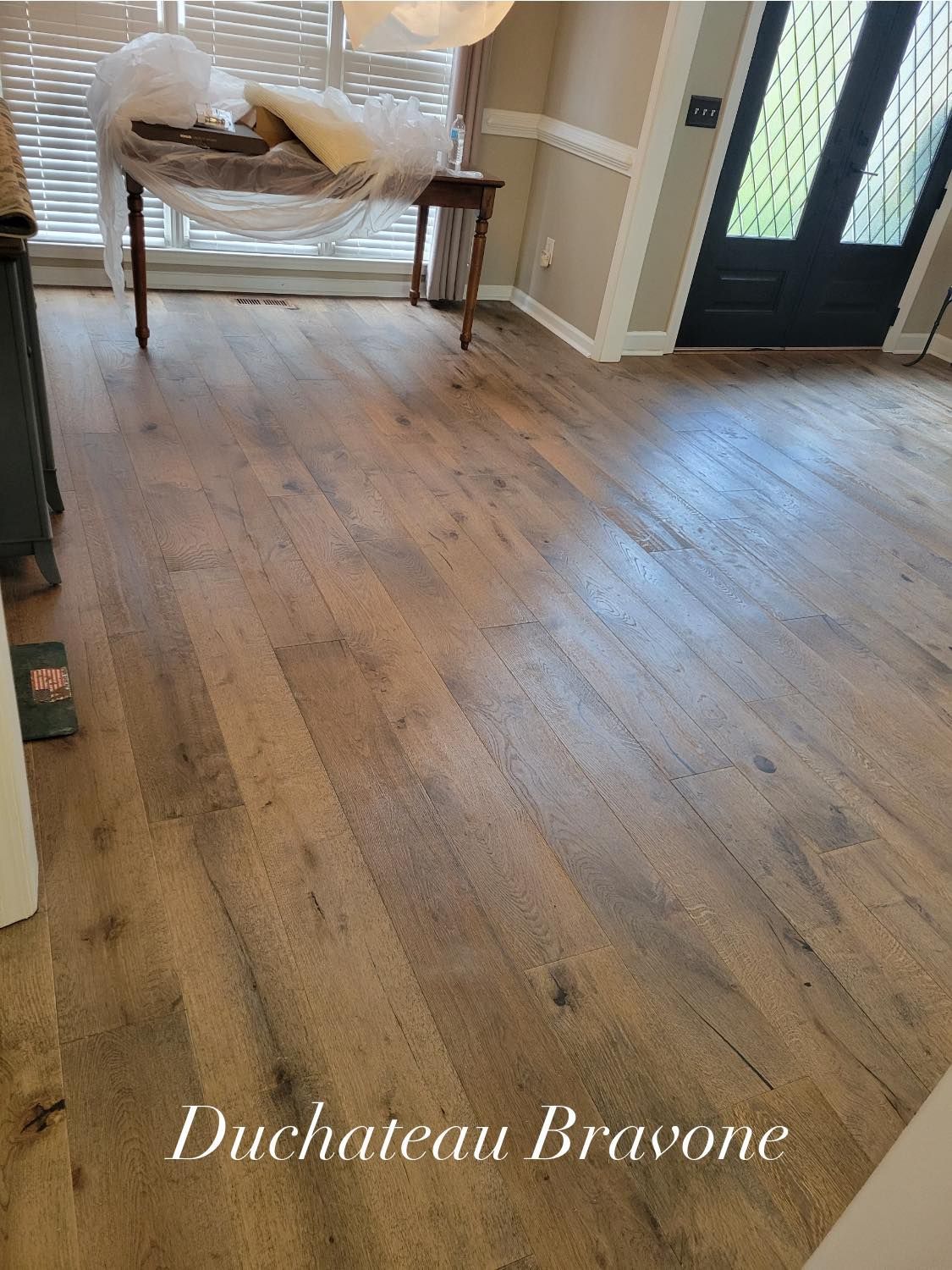 Light brown hardwood floor in a room. Some furniture in the background. 