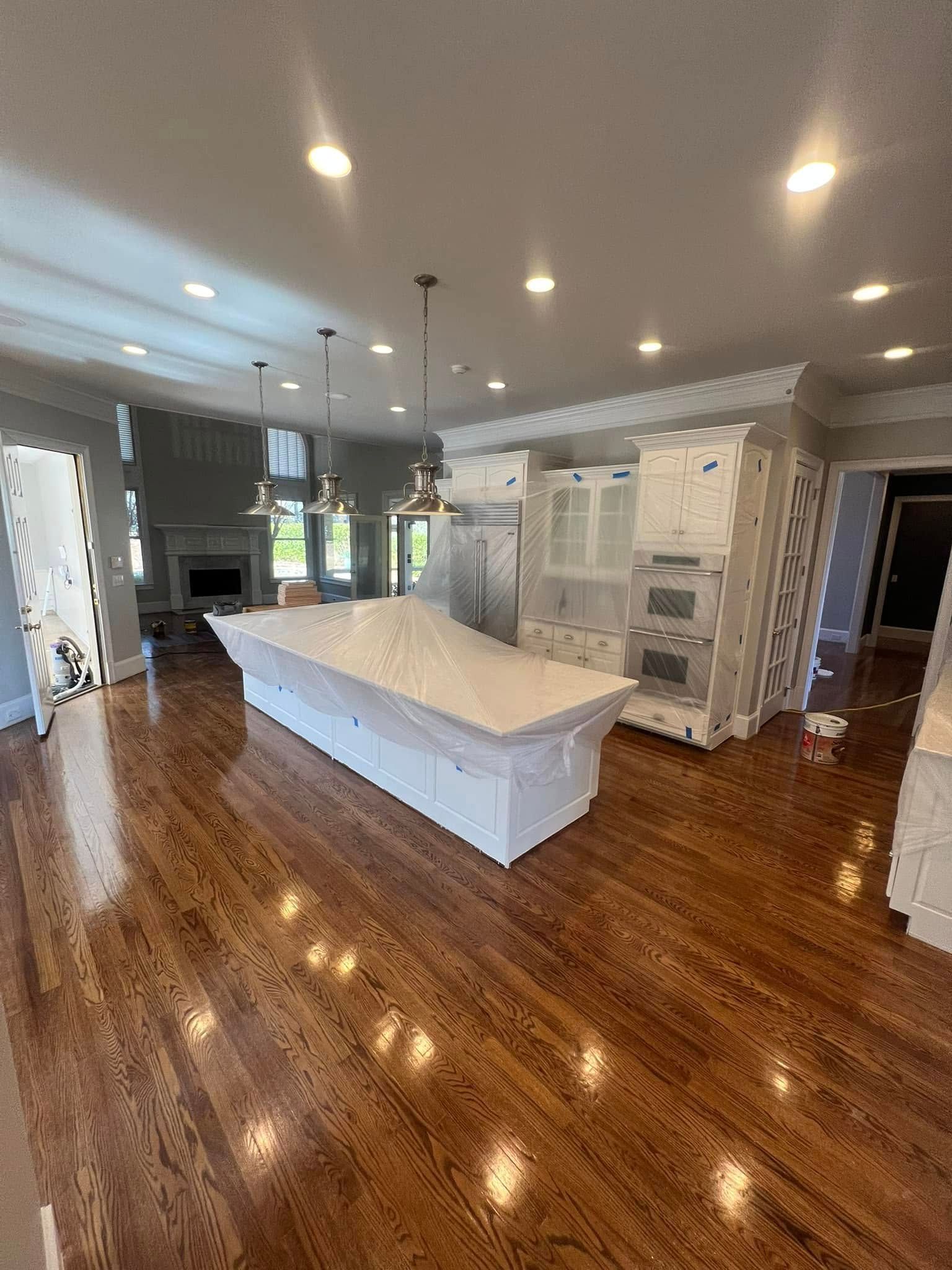 Spacious kitchen with a white island and cabinets, hardwood floors, and recessed lighting.
