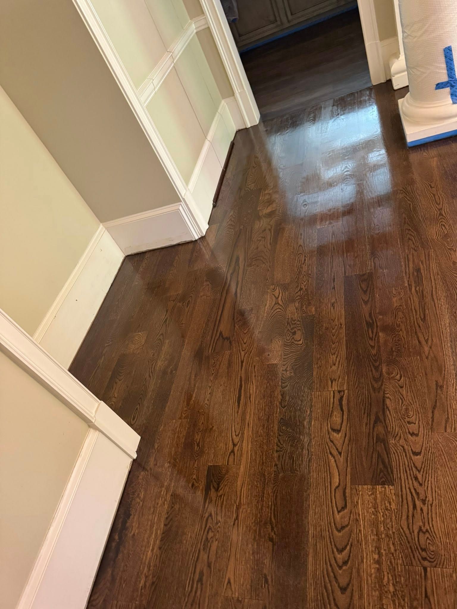 Dark stained hardwood floor next to white trim and built-in shelving with light tan walls.