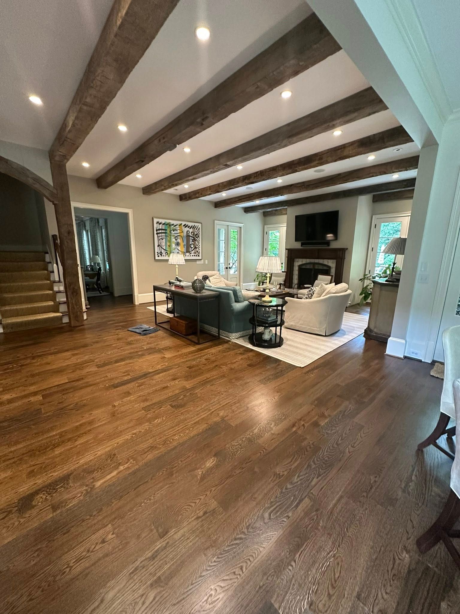 Living room with wood floors, exposed beams, fireplace, and sofas.