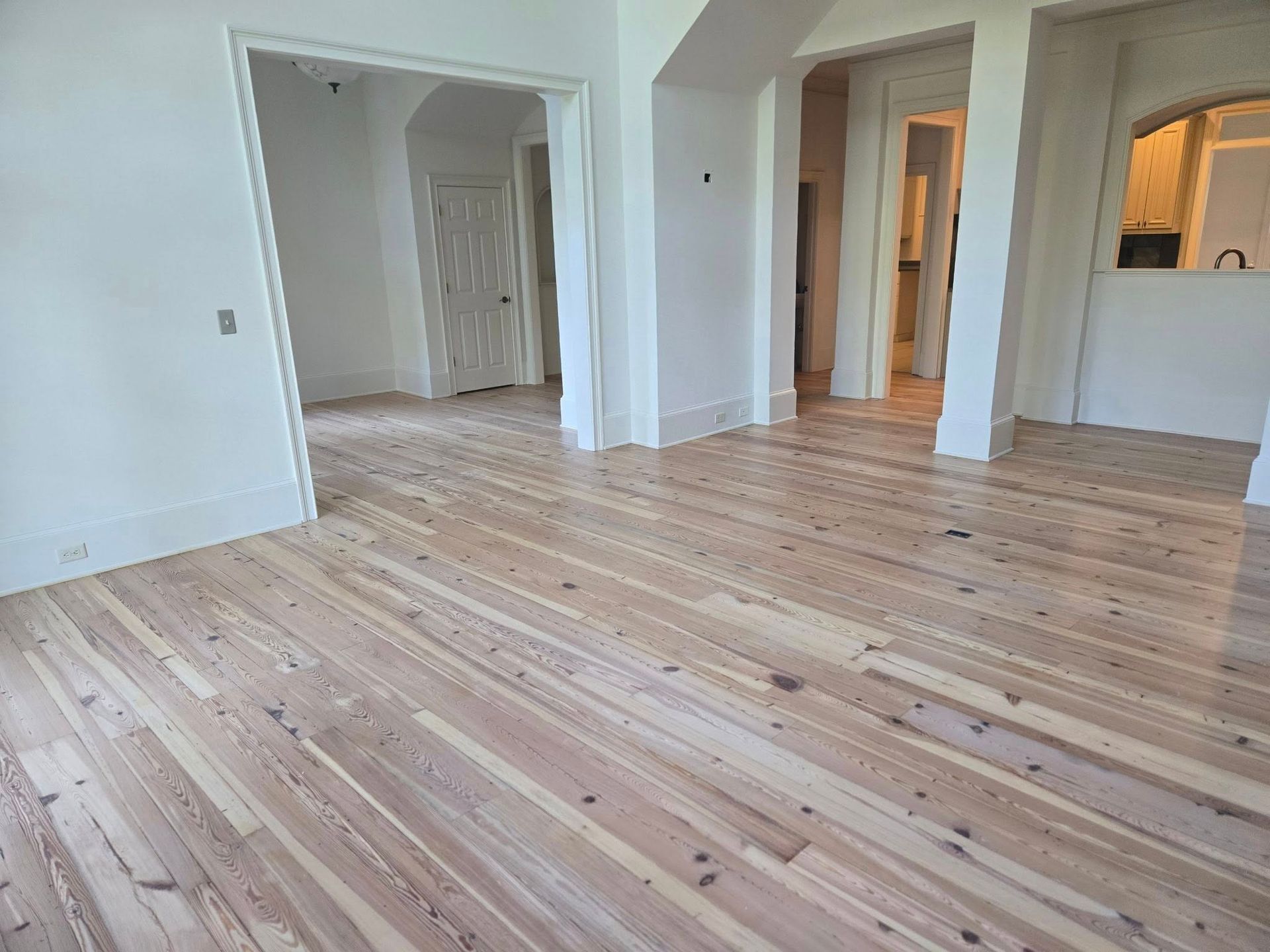 Light wood flooring in a room with white walls, doorways, and trim.
