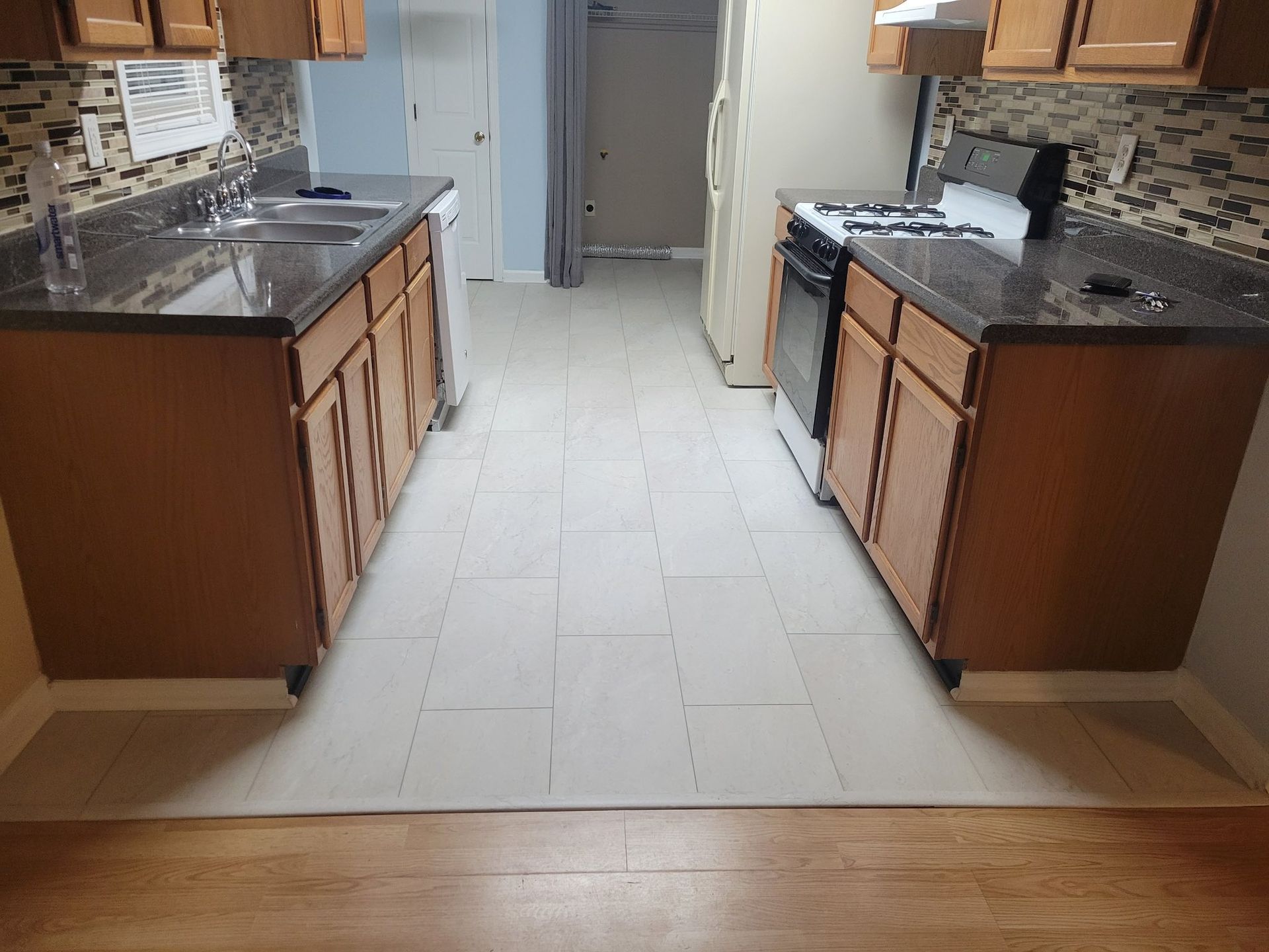 Kitchen with wood cabinets, dark countertops, beige tile floor, and a stove.