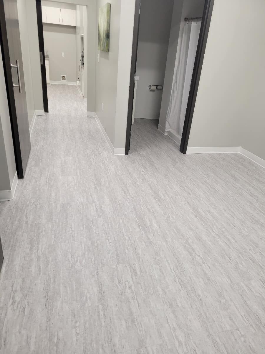 Light grey flooring in a hallway with doorways leading to other rooms.