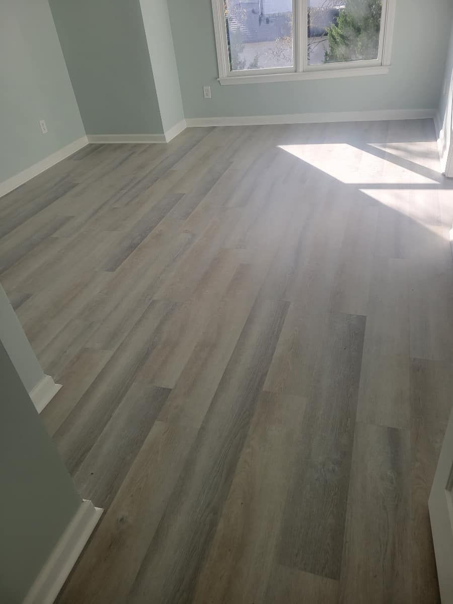 Light wood-look flooring in a room with light blue walls, white trim, and a window.